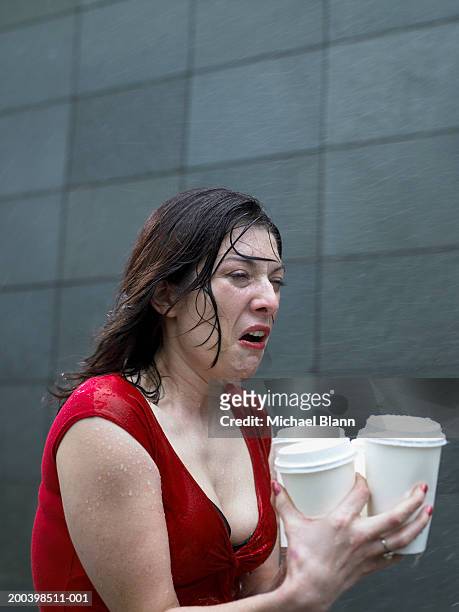 young woman carrying disposable cups in rain, pulling face - women taking showers stock pictures, royalty-free photos & images