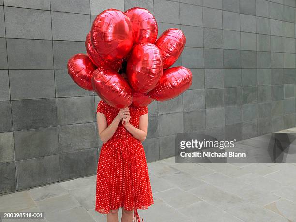 young woman holding bunch of red foil balloons, face obscured - red dress ストックフォトと画像