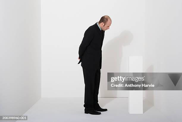 man looking at white block - confused white background stock-fotos und bilder