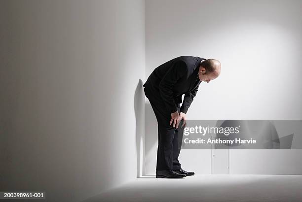 man crouching by small door in room - bukken stockfoto's en -beelden