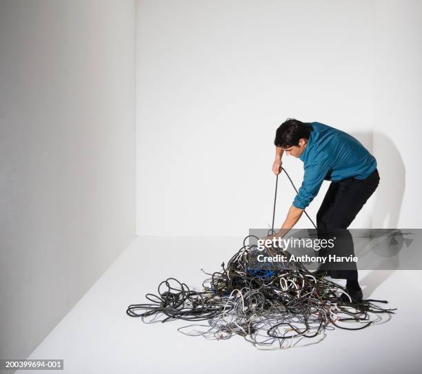 man pulling cable from pile of cables - emmêlé photos et images de collection