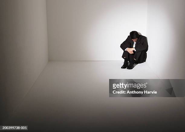 businessman sitting on floor in corner of room - hugging knees stock pictures, royalty-free photos & images