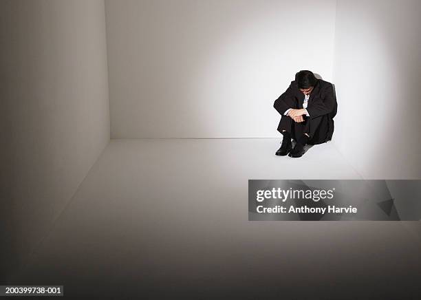 businessman sitting on floor in corner of room - hugging knees - fotografias e filmes do acervo