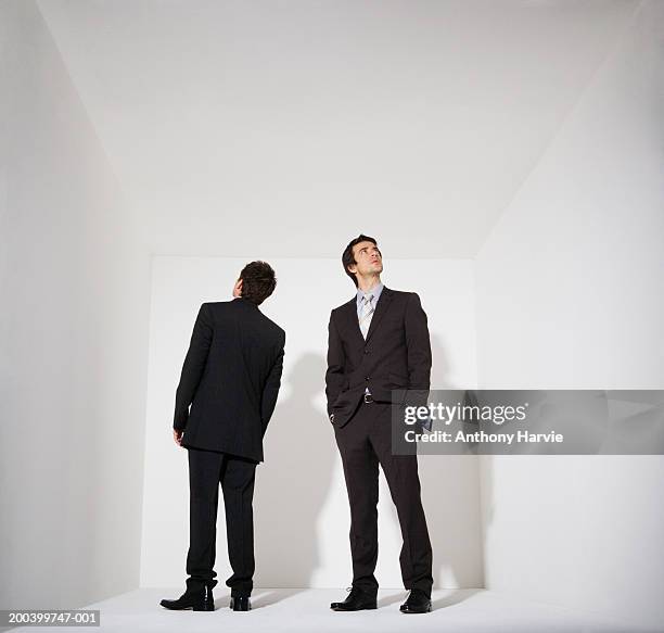 two businessmen standing in white room - confused white background stock-fotos und bilder