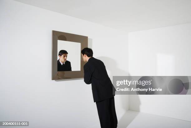 businessman looking at reflection in mirror on wall - spiegel stock-fotos und bilder