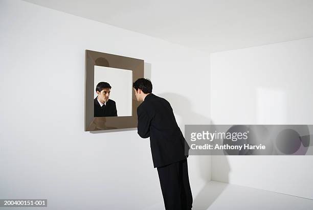 businessman looking at reflection in mirror on wall - solo un uomo foto e immagini stock