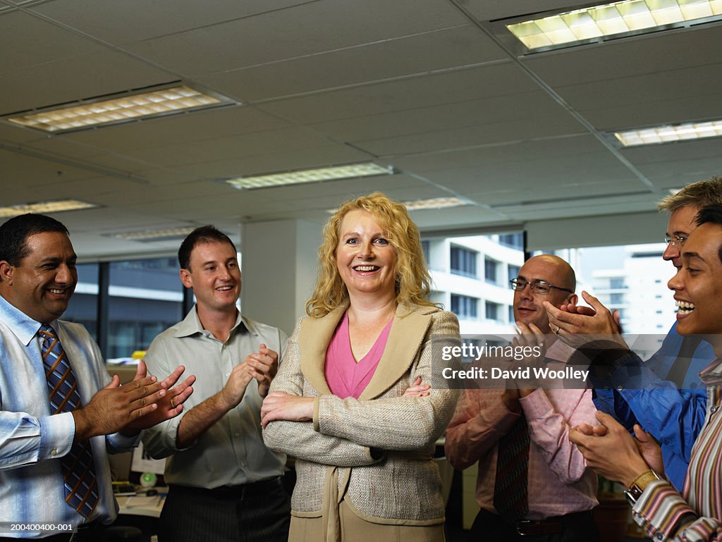 Businessman applauding female colleague in office