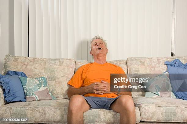 senior man relaxing on couch, laughing, hands clasped - huvudet bakåt bildbanksfoton och bilder