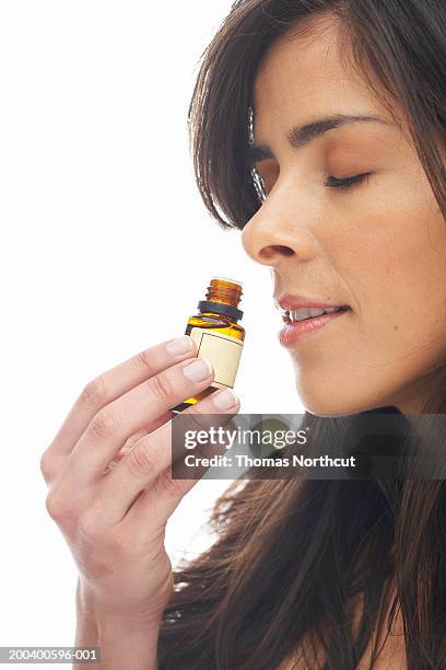 young woman smelling aromatherapy oil, eyes closed - aromatherapy oil stock pictures, royalty-free photos & images
