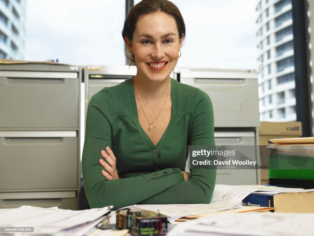 Young businesswoman at desk, smiling, portrait