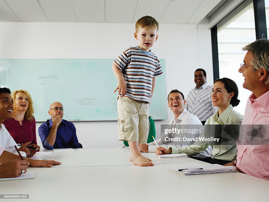 Boy (2-4) standing on table in business meeting