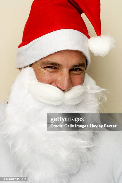 young man wearing santa hat and beard, portrait, close-up - santa close up stock-fotos und bilder