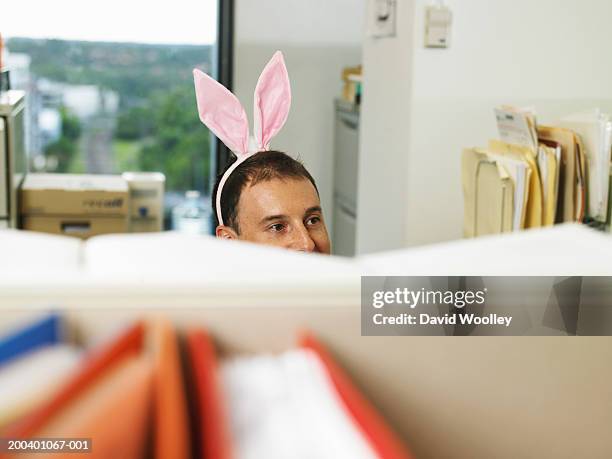 man wearing bunny ears in office, desk divder in foreground - costume rabbit ears stock pictures, royalty-free photos & images