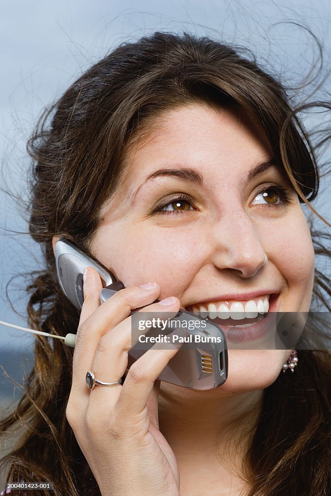 Young woman using mobile phone, smiling, close-up