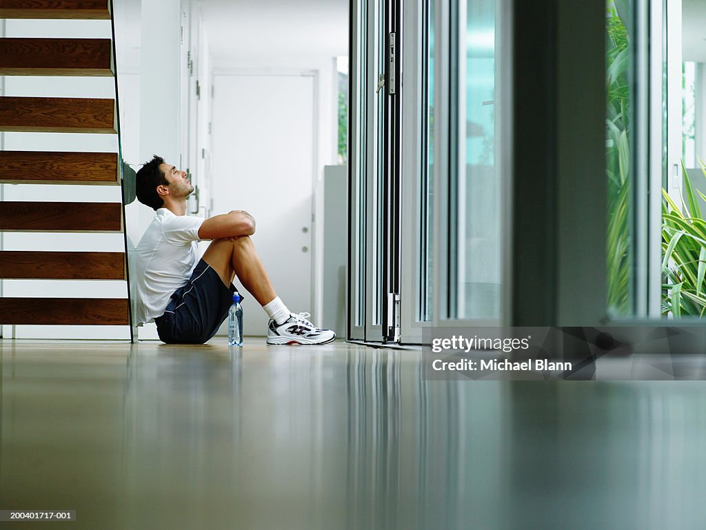 Man in sports clothes sitting on hall floor, ground view