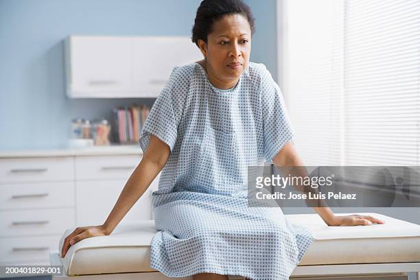 female patient sitting on examination table in doctor's office - tavolo da visita foto e immagini stock