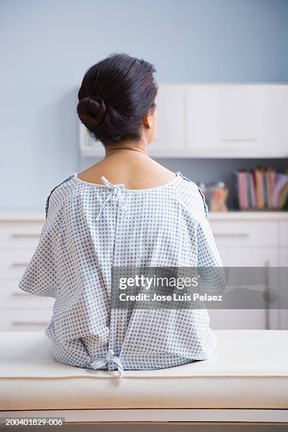 female patient sitting on examination table, rear view - examination gown stock pictures, royalty-free photos & images
