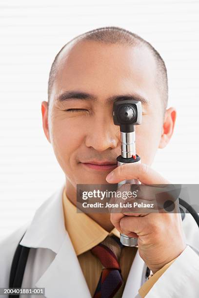 doctor looking through a otoscope - otoscope fotografías e imágenes de stock