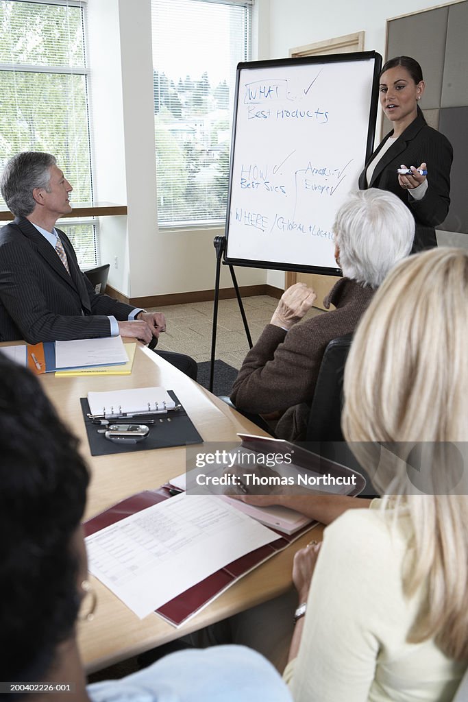 Businesswoman using whiteboard during meeting with executives