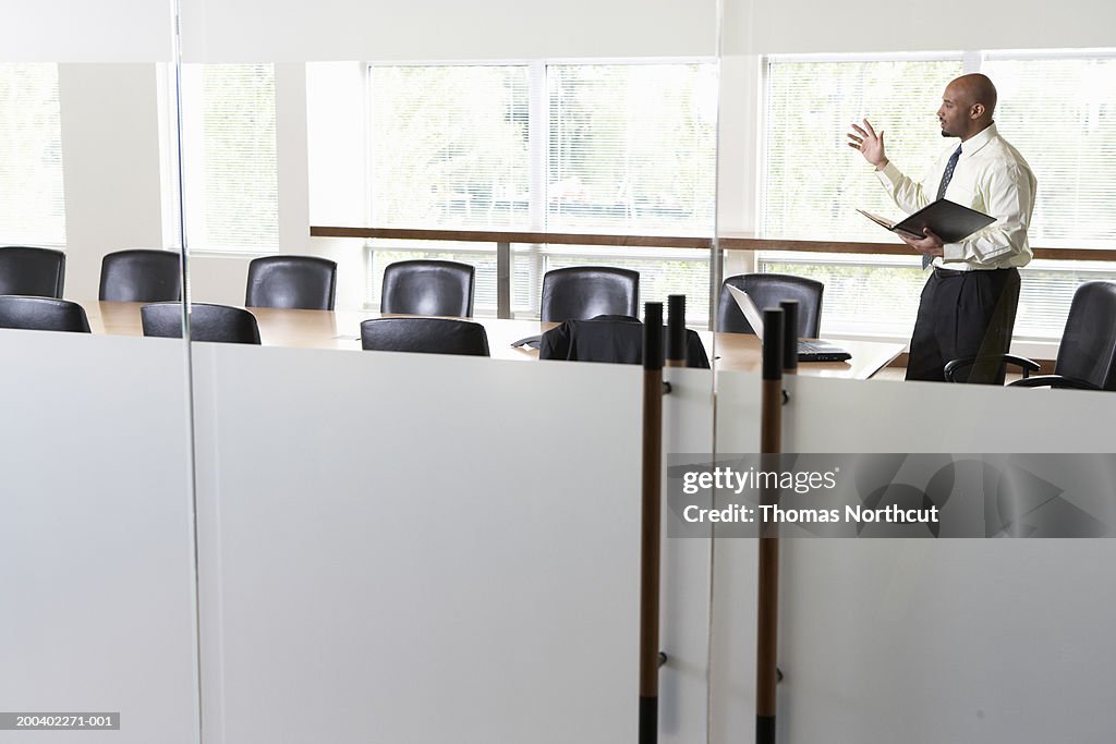 Businessman practicing presentation in boardroom, side view
