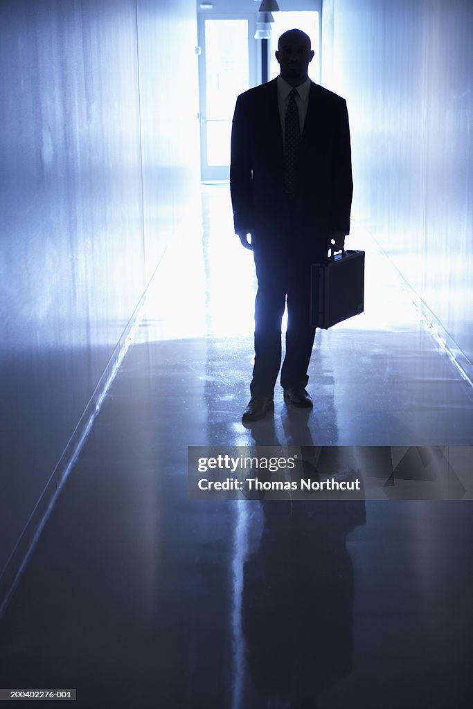 Silhouette of businessman holding briefcase in corridor