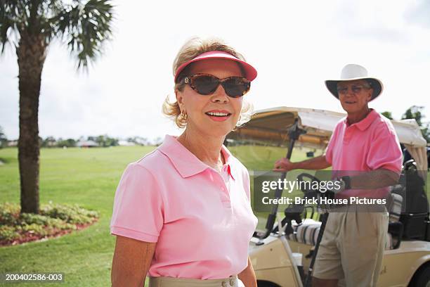 senior couple on golf course, portrait - サンバイザー ストックフォトと画像