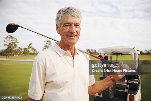 senior man holding golf club, golf cart in background, portrait - senior men golf stock pictures, royalty-free photos & images