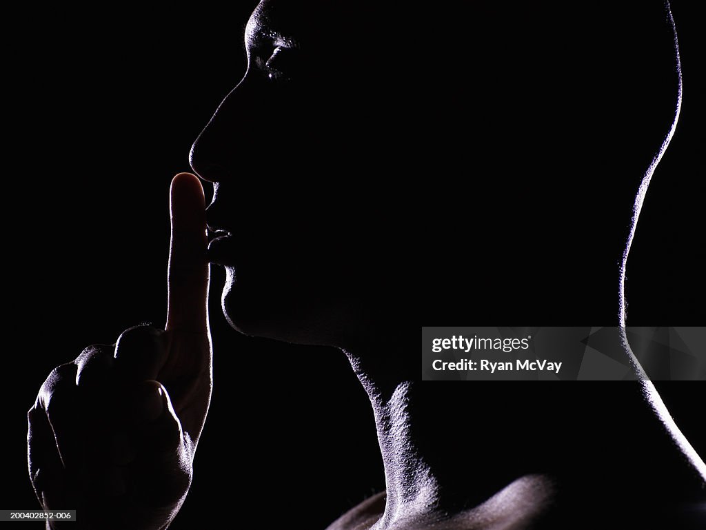 Man with finger on lips, side view