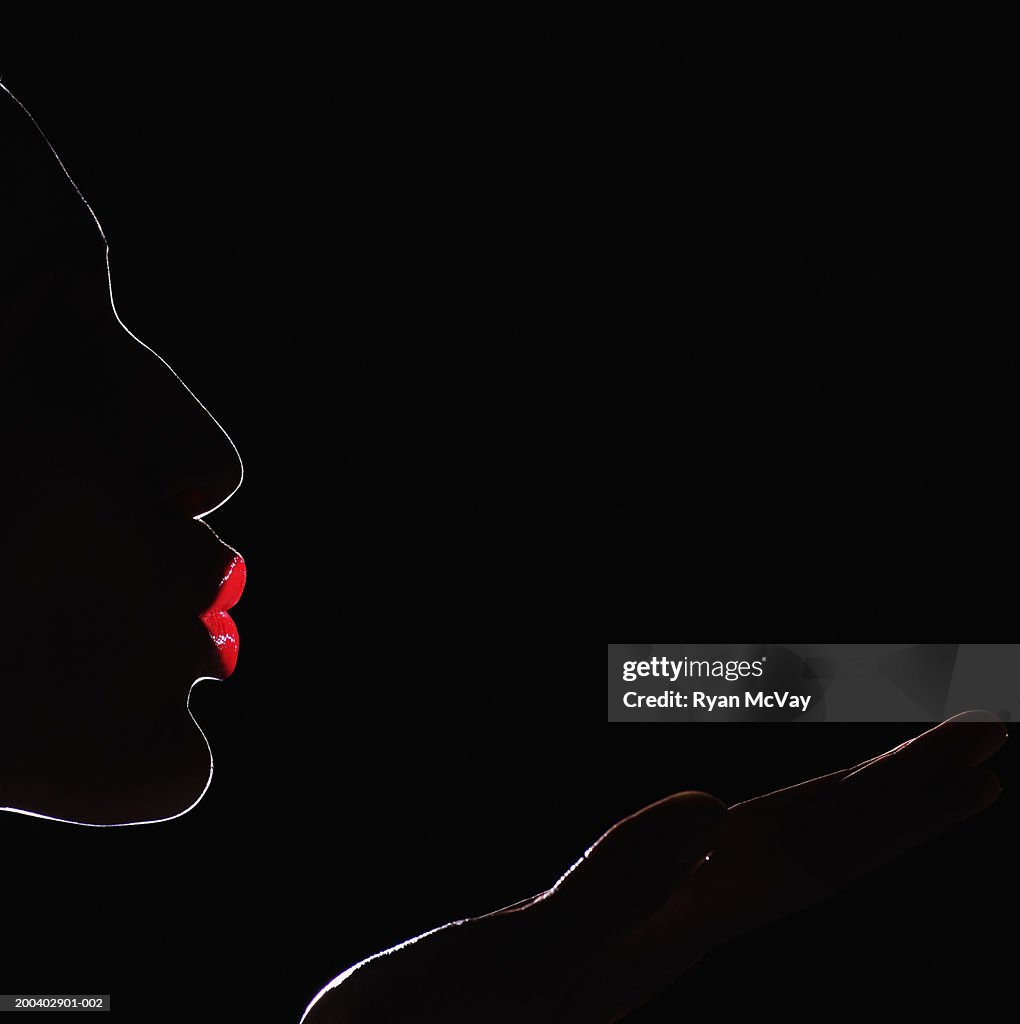 Young woman blowing kiss, profile