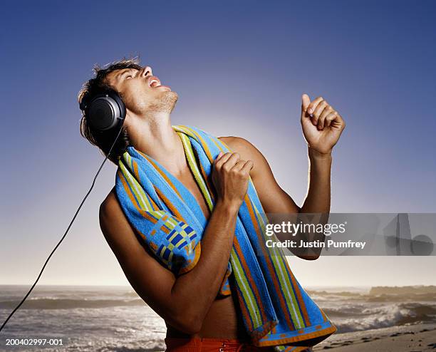 man dancing on beach wearing headphones, towel around neck, close-up - headphone man on neck stock pictures, royalty-free photos & images