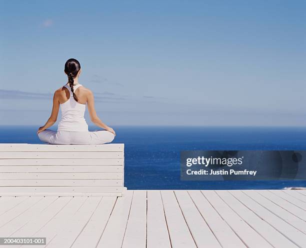 young woman meditating on wooden block, rear view - 胡坐　横 ストックフォトと画像