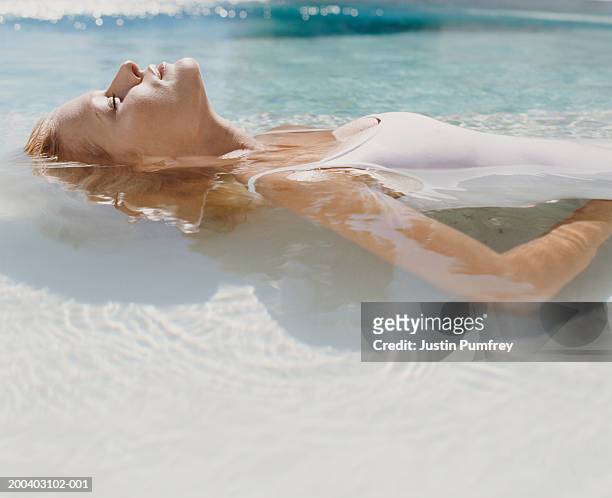 young woman lying back in water, eyes closed, side view, close-up - human hair stock pictures, royalty-free photos & images