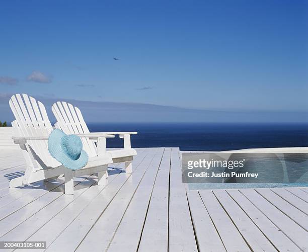 two wooden chairs on decking by outdoor pool - adirondack chair stock pictures, royalty-free photos & images