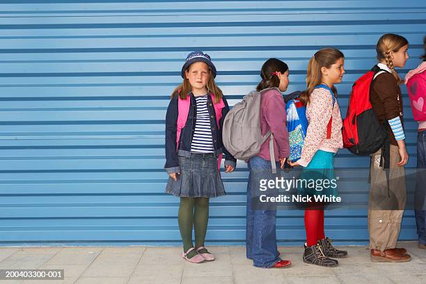 children (8-11) queuing along wall, portrait of girl at end of queue - kids lining up stock pictures, royalty-free photos & images