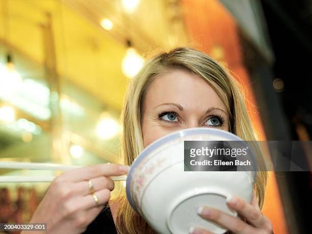 woman eating noodles, bowl obscuring mouth, low angle view - chopsticks stock-fotos und bilder