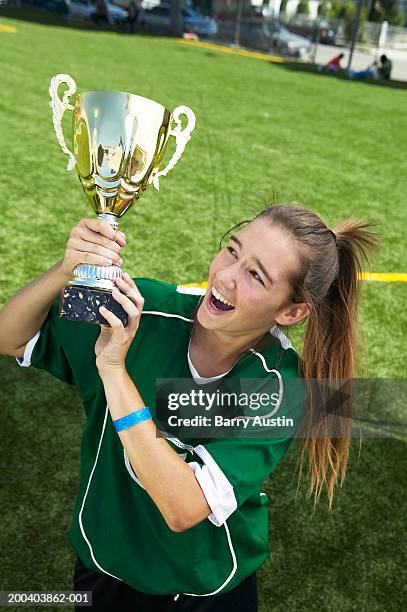 female footballer (13-15) holding up trophy, smiling, elevated view - alleen één tienermeisje stockfoto's en -beelden