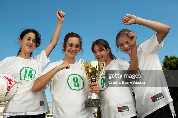 female footballers (13-15) holding trophy, arms raised in celebration - championship day four stockfoto's en -beelden