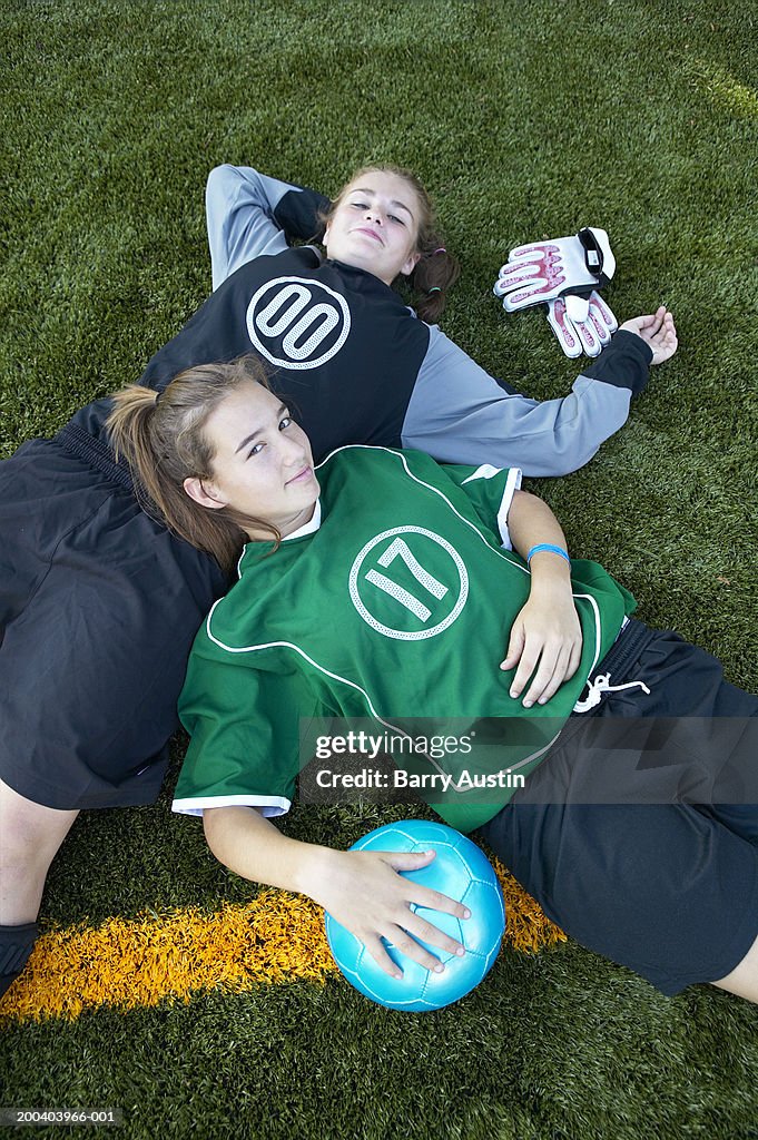 Female footballers (13-15) lying on pitch, portrait, elevated view