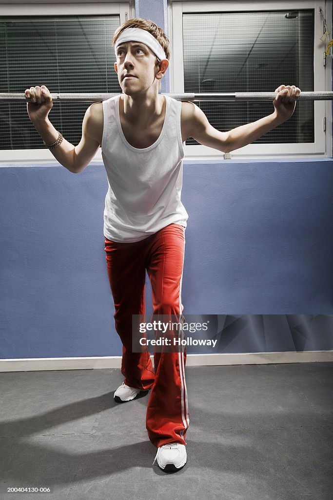 Young man wearing sweatband lifting weight in gym