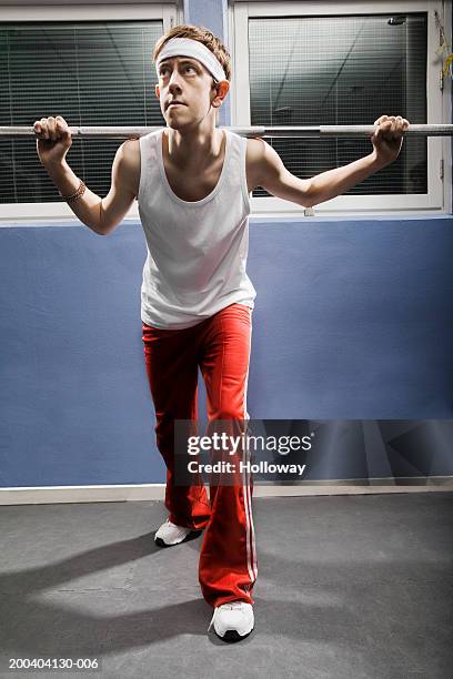 young man wearing sweatband lifting weight in gym - stereotypical stock pictures, royalty-free photos & images