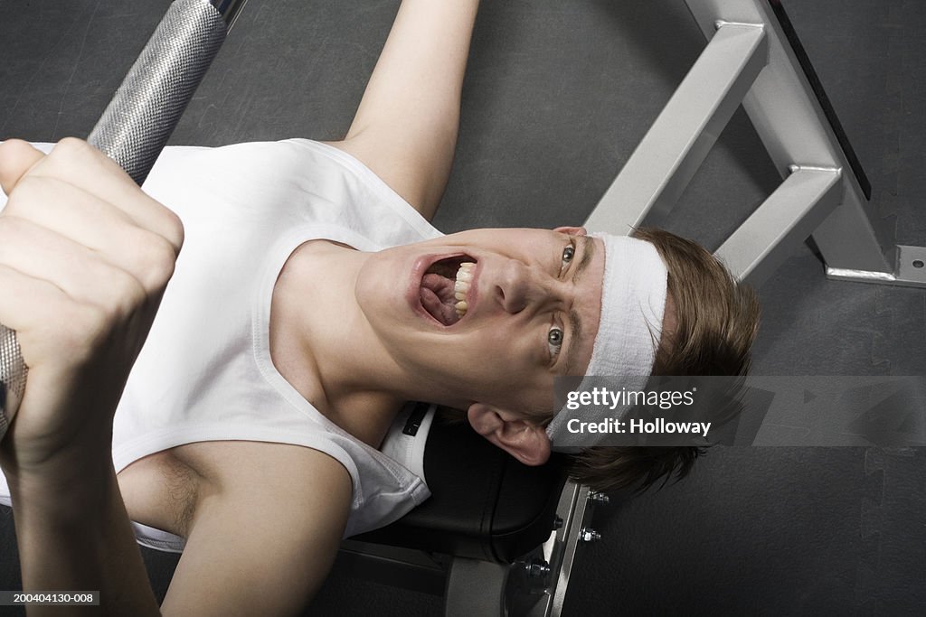 Young man lifting weight, overhead view, close-up