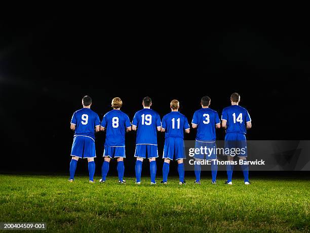 six young male soccer players standing side by side, rear view - voetbalteam stockfoto's en -beelden