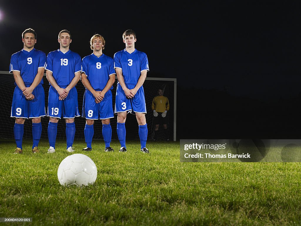 Young male soccer players in defensive wall, awaiting free kick