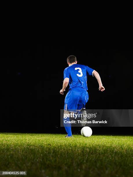 young male soccer player dribbling ball, rear view - fußballtrikot rücken stock-fotos und bilder