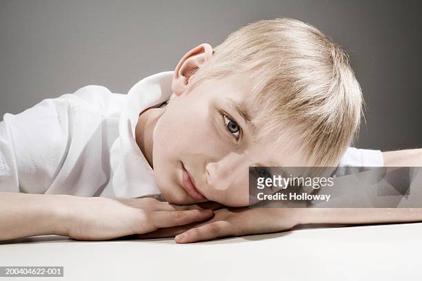 boy (11-13) leaning on table, resting head on hands, close-up - head on table stock-fotos und bilder