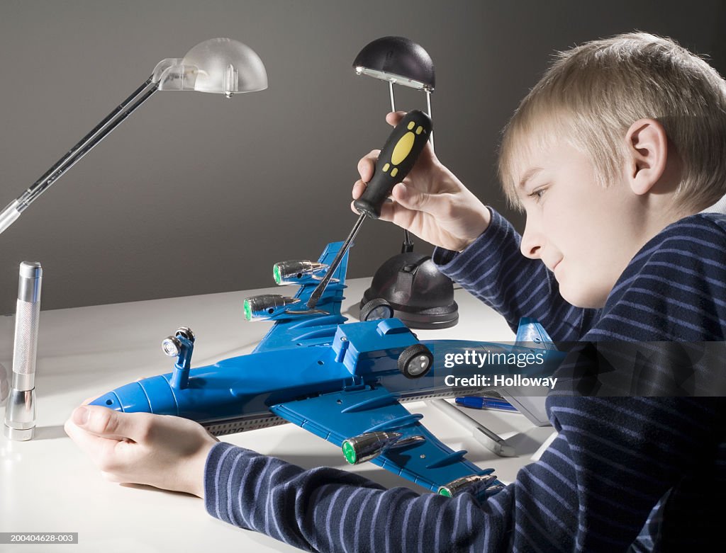 Boy (11-13) building model aeroplane, smiling