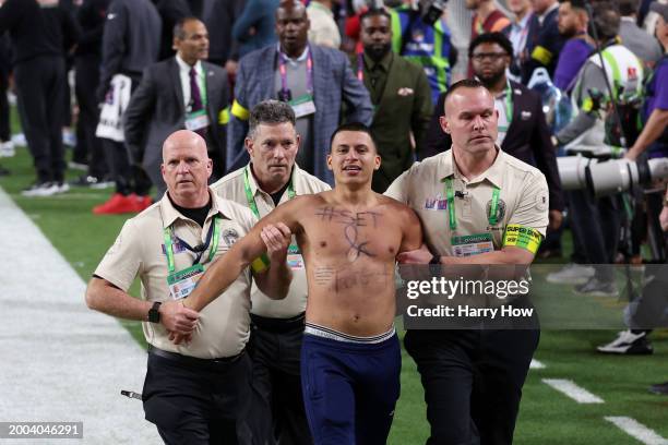 Sebastian Rivera is escorted away after running onto the field in the third quarter during Super Bowl LVIII between the San Francisco 49ers and...