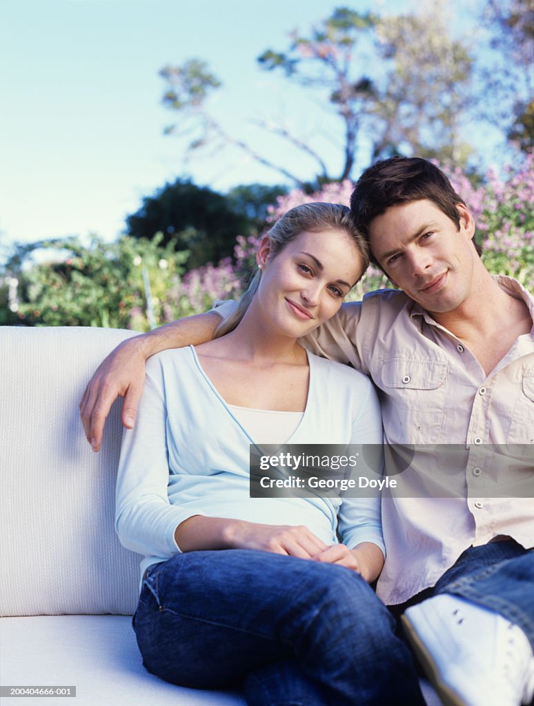 Young couple sitting, smiling, portrait