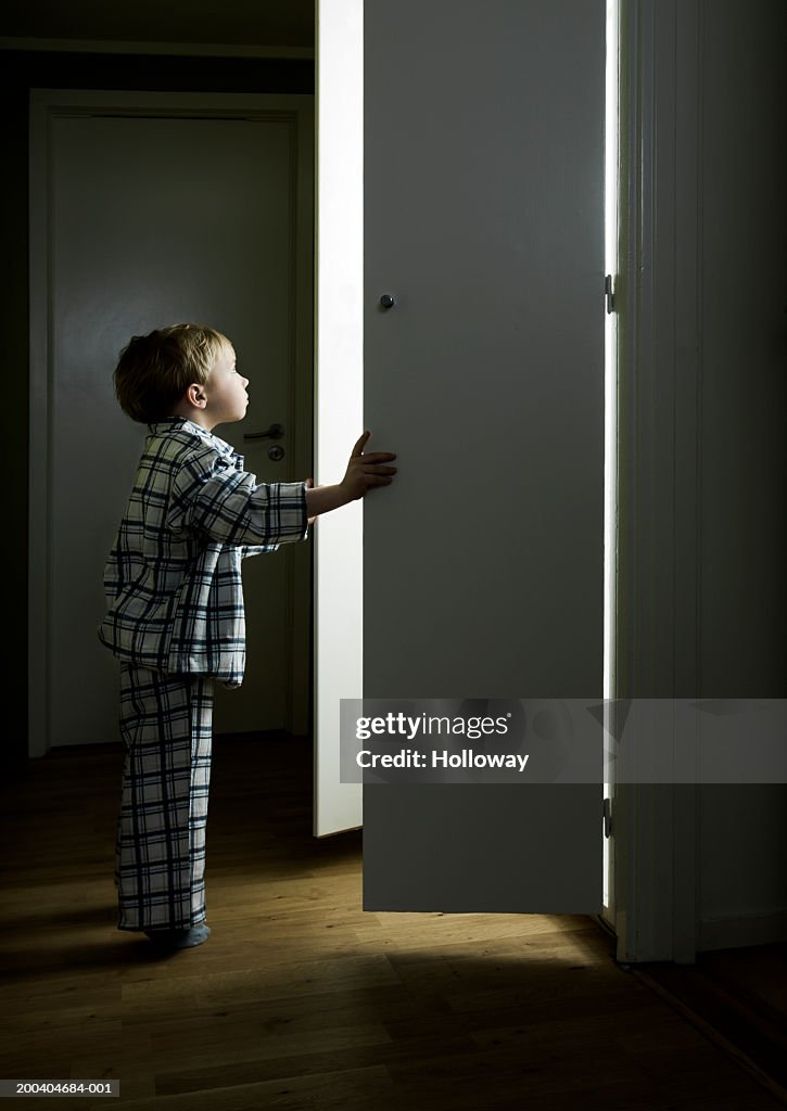 Boy (2-4) opening cupboard doors standing in light