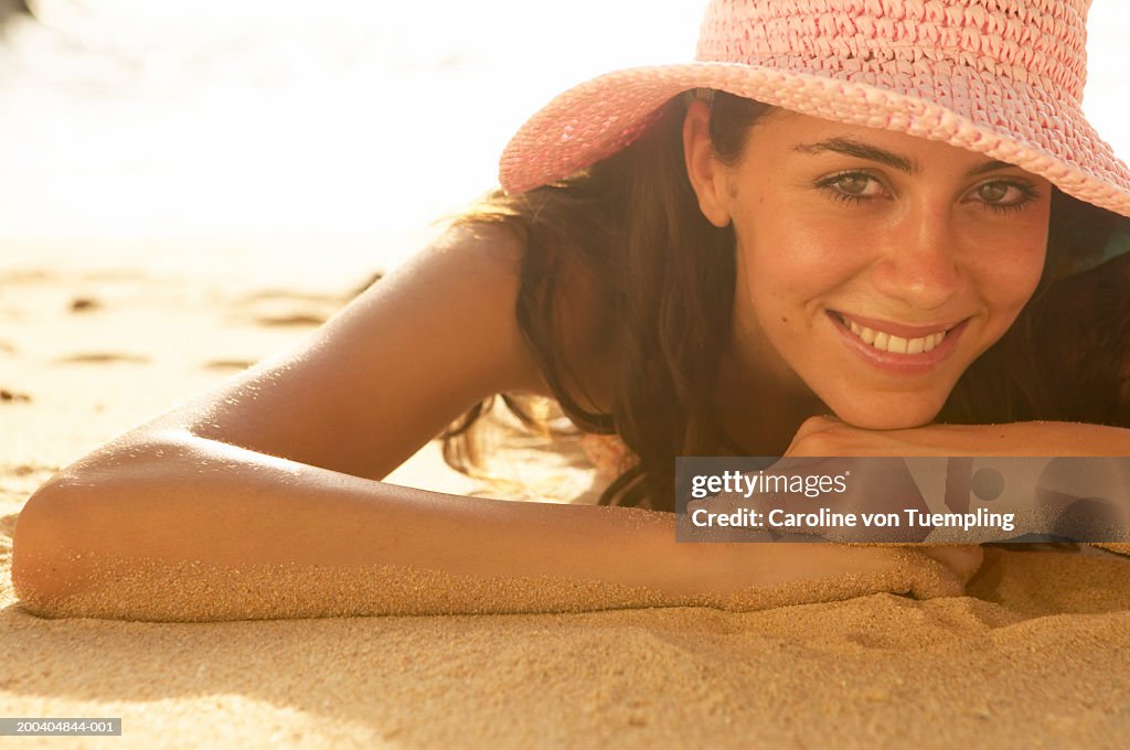 Woman wearing hat on beach smiling, portrait